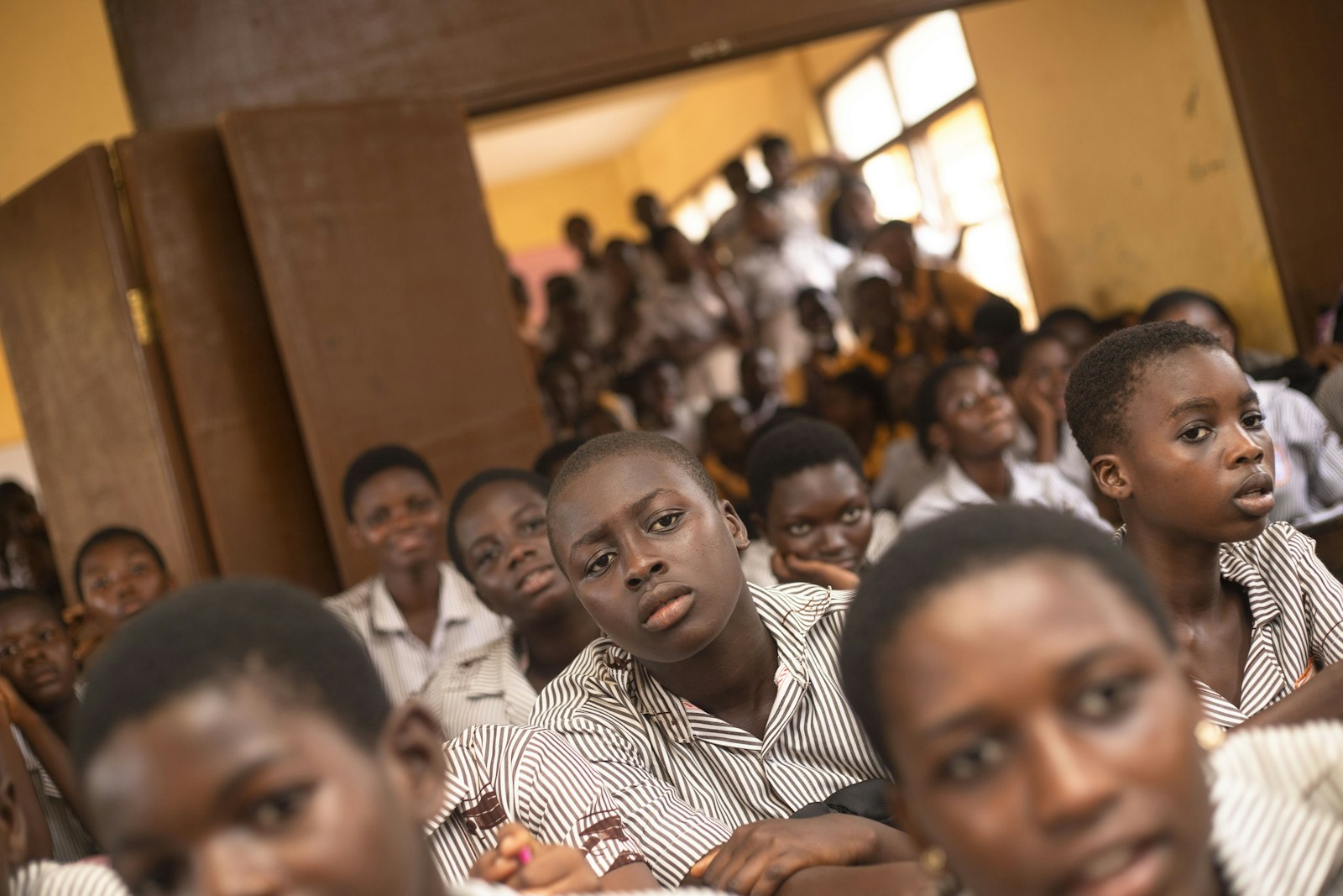 A packed classroom of students sharing benches